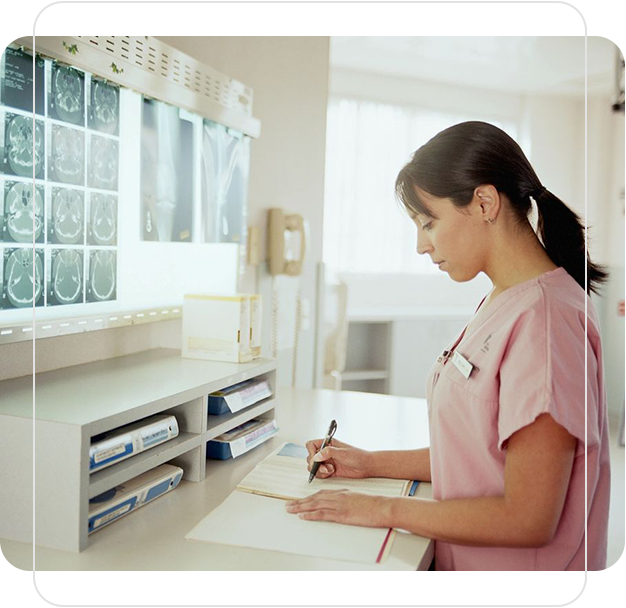 A woman in pink scrubs writing on paper.